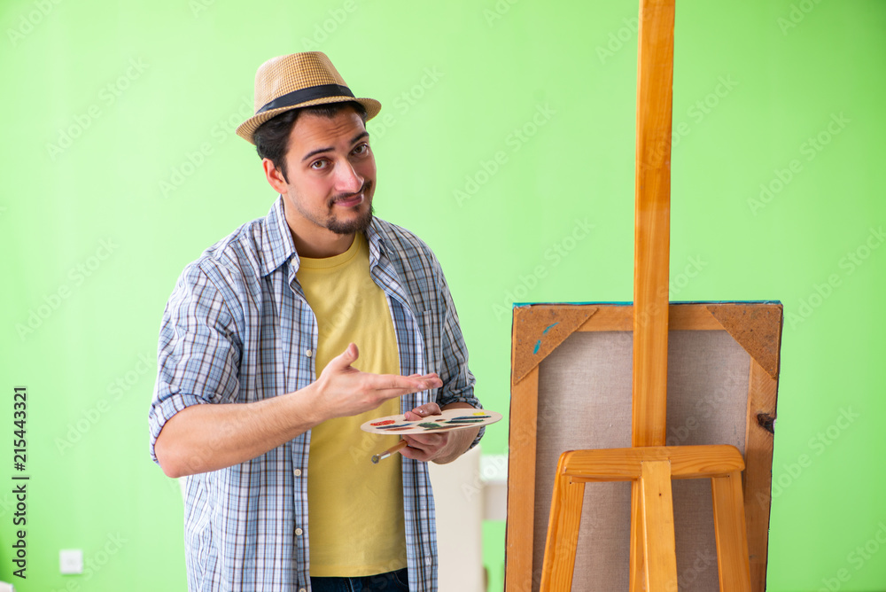 Young male artist working on new painting in his studio Young male artist working on new painting in his studio