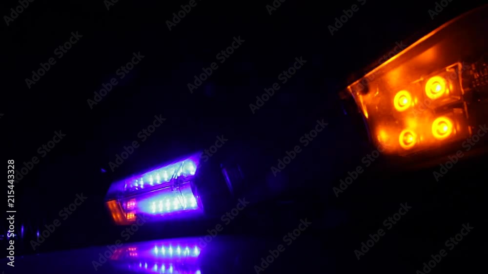 Luces Intermitentes de advertencia lanzando flash de colores en coche de la policia por la noche Luces Intermitentes de advertencia lanzando flash de colores en coche de la policia por la noche