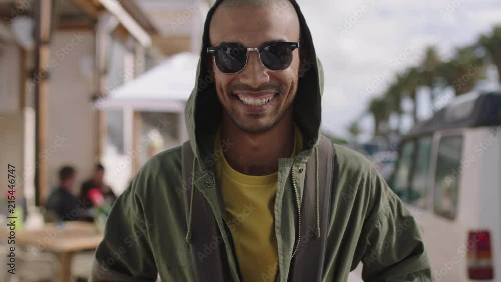 portrait of handsome hispanic man smiling happy on sunny beachfront wearing hoodie portrait of handsome hispanic man smiling happy on sunny beachfront wearing hoodie