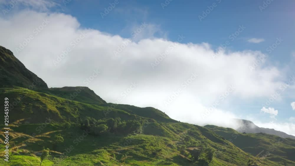 Low foggy clouds rolling fast over hilltop on sunny but windy day in realtime over green valley near Napier New Zealand Low foggy clouds rolling fast over hilltop on sunny but windy day in realtime over green valley near Napier New Zealand