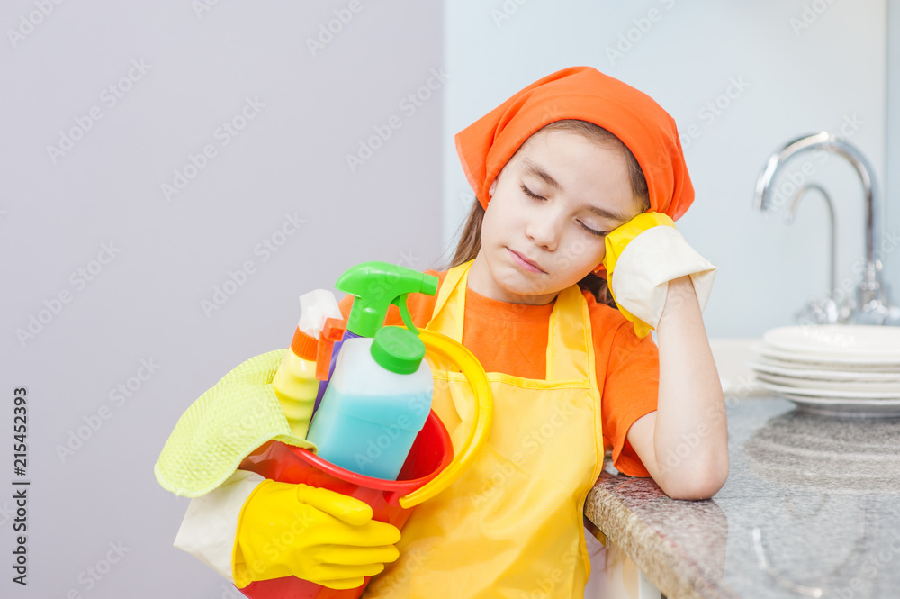 Tired little girl with cleaning supplies in bucket at kitchen Tired little girl with cleaning supplies in bucket at kitchen