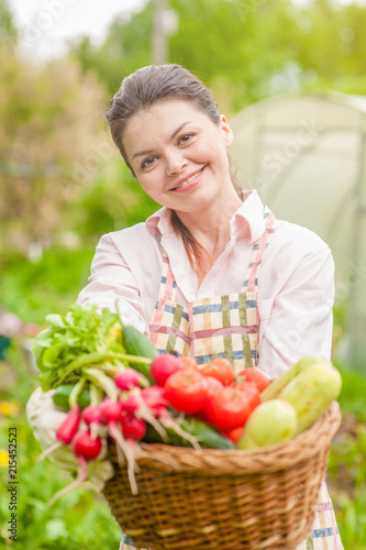 Happy woman with fresh vegetables in the basket in her hands