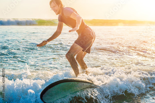 Obraz na plátně Young man, beginner Surfer learns to surf on a sea foam on the Bali island