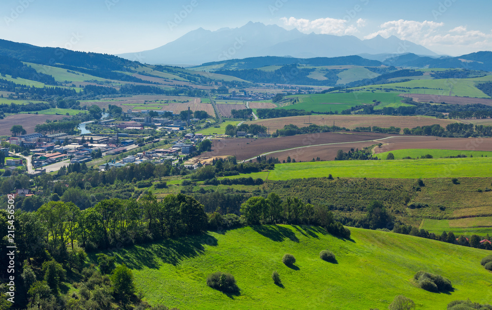 rural area around the town. grassy hill and agricultural fields. High tatra mountain ridge in the distance. view from the top of a castle tower