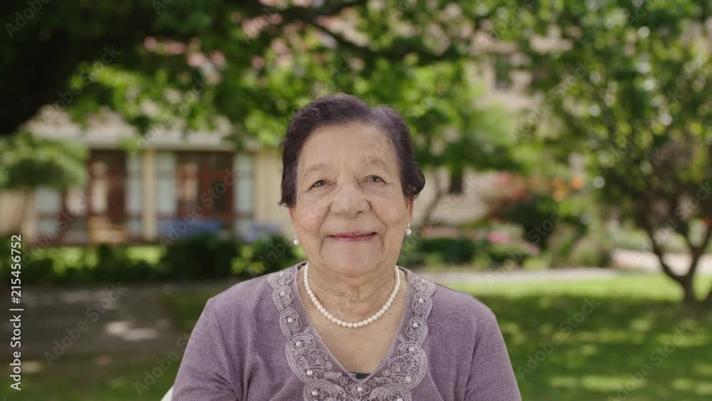 portrait of beautiful elegant elderly woman smiling at camera wearing pearl necklace in garden background portrait of beautiful elegant elderly woman smiling at camera wearing pearl necklace in garden background