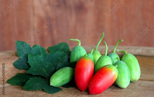 Lvy Gourd or cocconia grandis fruit with leaves on wooden background. photo