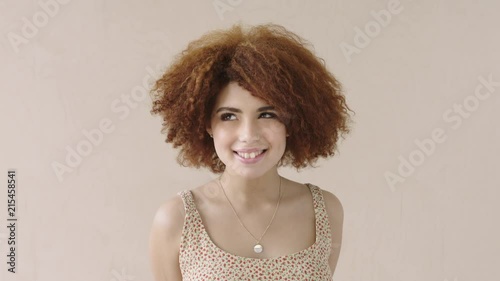 portrait of young shy mixed race woman with afro smiling bashful student 