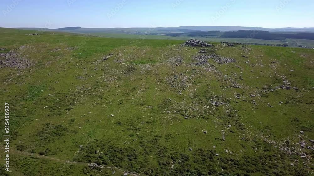Wide aerial shot that pans from left to right over a glorious green glass moorland with rocks scattered across the land. Dartmoor, Devon, England Wide aerial shot that pans from left to right over a glorious green glass moorland with rocks scattered across the land. Dartmoor, Devon, England
