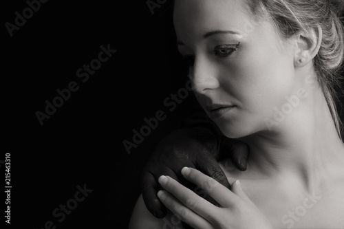 Beautiful blonde woman with black hand of a man on her shoulder artistic conversion