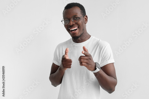 Young african american man pointing to camera with fingers isolated on gray background. Hey you!