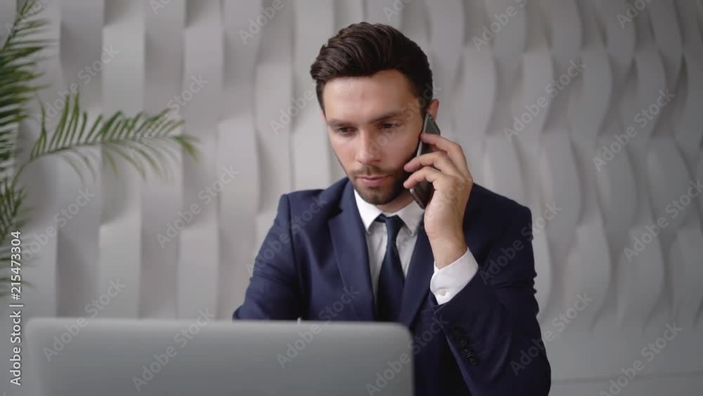 Handsome young businessman on smartphone in office Handsome young businessman on smartphone in office