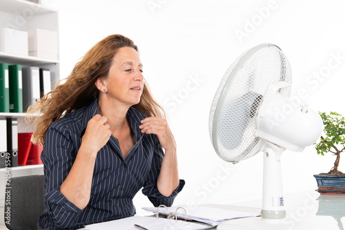 young business woman with ventilator at his desk in summerly hot o photo