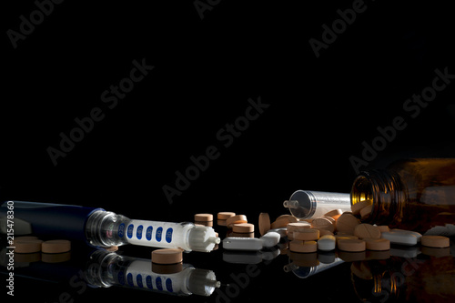 insulin injection pen and a lot of Medicine tablet for diabetes patient with black background photo