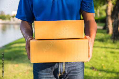 Delivery man in blue uniforms holding parcel cardboard box.