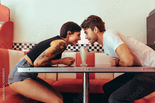 Photos Couple sharing a glass of milk shake at a diner