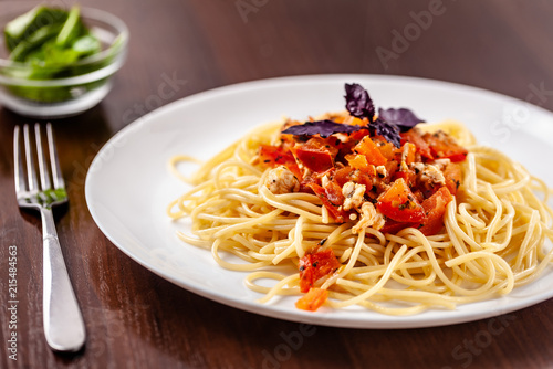 Italian pasta spaghetti with red tomato sauce, tomatoes and grilled chicken. It is on the table in the restaurant. Copy space, selective focus