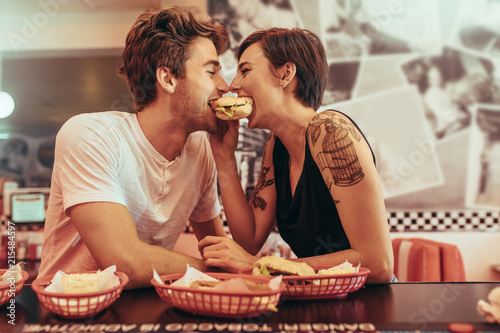 Coupe in romantic mood sharing a burger at a restaurant photo