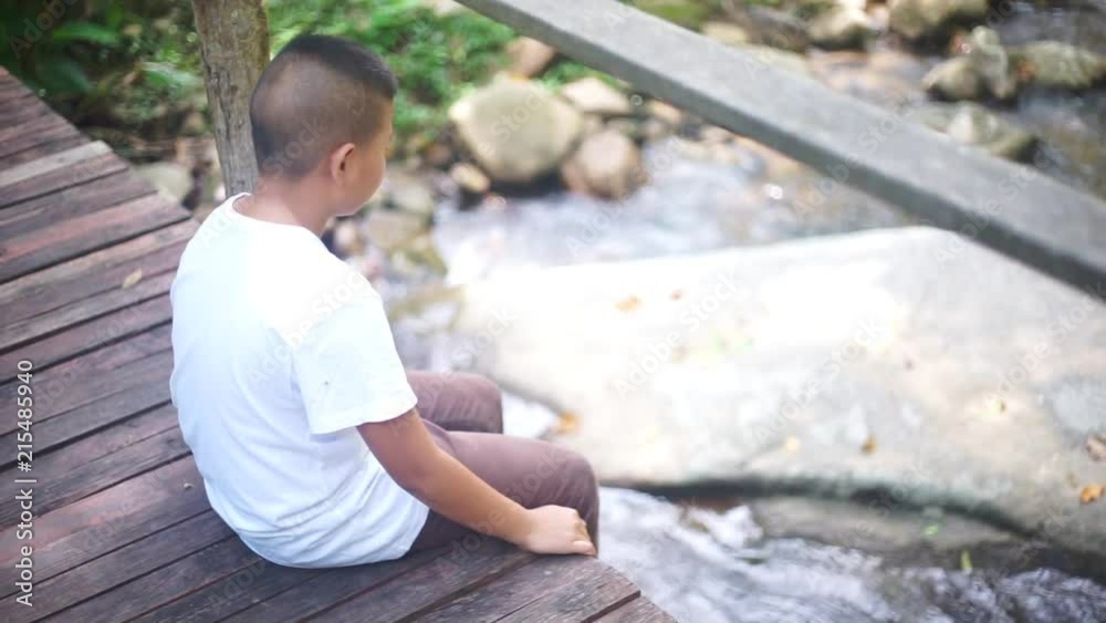 Sad young Asian boy sitting alone Sad young Asian boy sitting alone