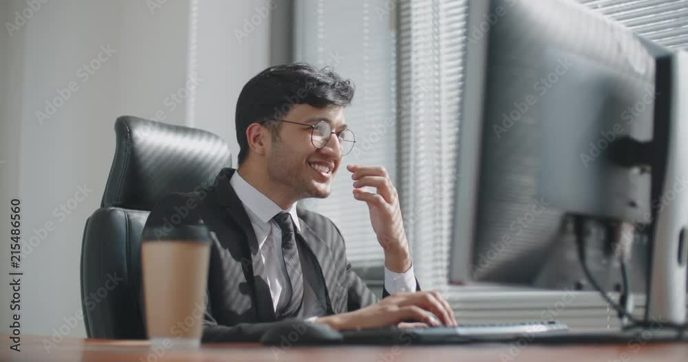 young iranian businessman working at computer in office, then celebtating successful business deal. business, victory concept 4k young iranian businessman working at computer in office, then celebtating successful business deal. business, victory concept 4k