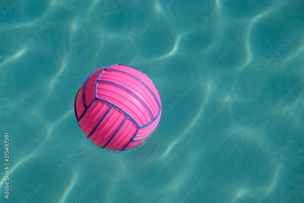 Pink ball with blue stripes on a blue water surface