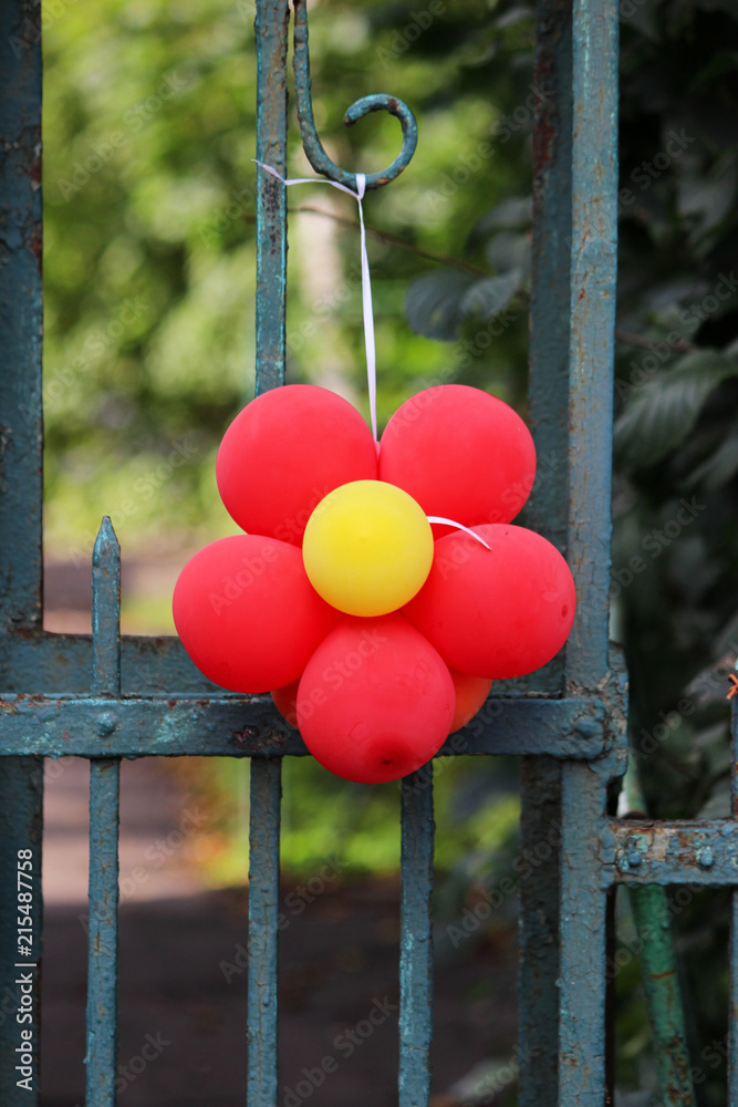 red flower made from a balloon hanging on a fence. red flower made from a balloon hanging on a fence.