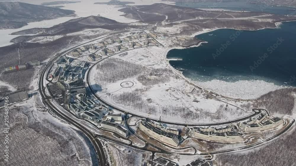 Drone High altitude Far Eastern Federal University FEFU Summit Vladivostok Russia. Modern building education Isle quay Russian blue water sea cityscape. Winter cold snow frozen Sun day blue sky Aerial