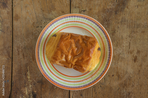 Traditional french chocolate bread on plate and vintage wooden background top view photo