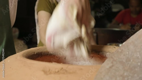 Baker making turkish pita bread in tandoor, clay oven. Baking process. photo