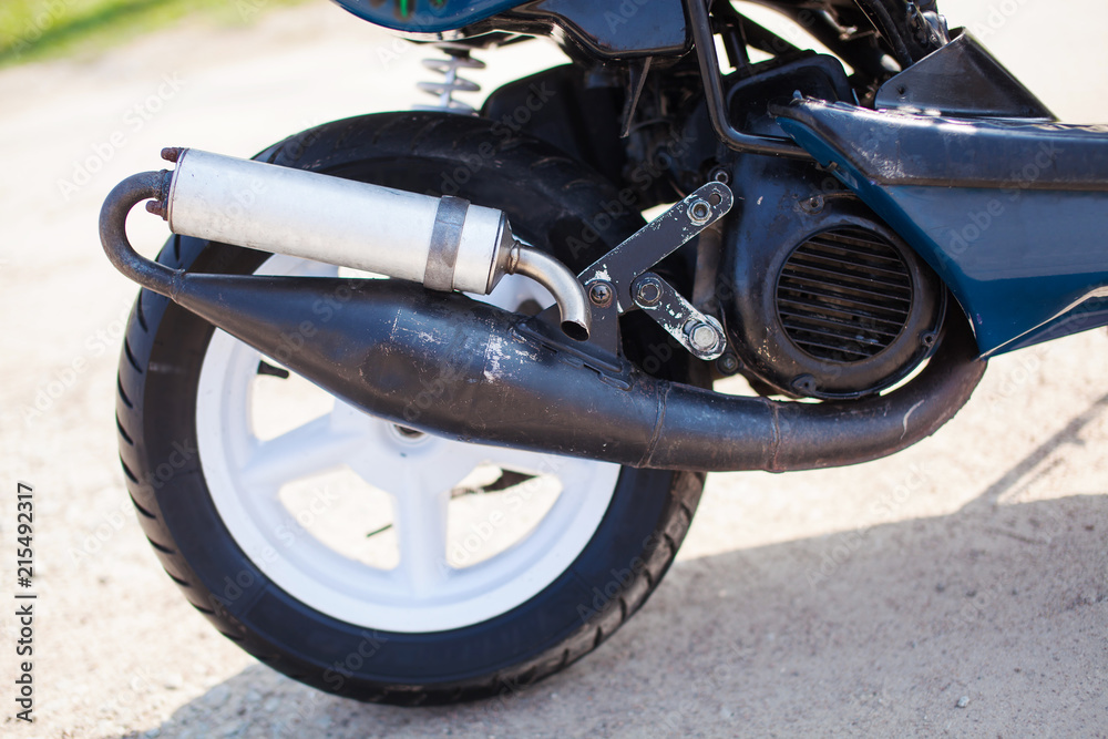 Obraz premium Rear wheel with exhaust of blue modern scooter on the gravel road