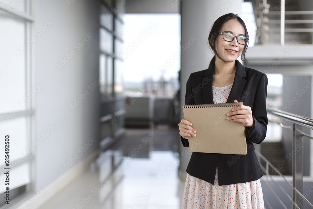 Young Asian business woman wear suit holding file document, standing at office Young Asian business woman wear suit holding file document, standing at office