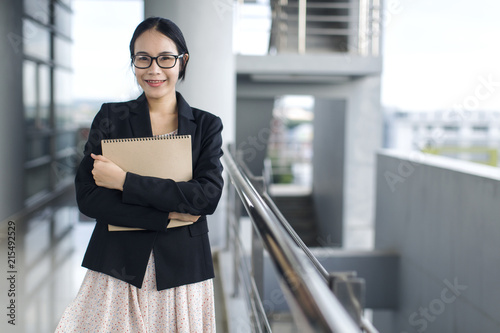 Canvas Print Young Asian business woman wear suit holding file document, standing at office