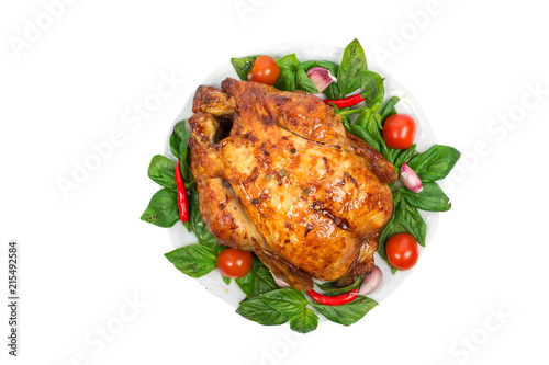 Whole roasted chicken grill on a plate with basil, tomatoes and chili pepper isolated on white background