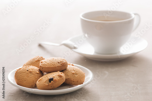 Coffee. White porcelain cup of freshly brewed coffee top view close-up arranged with  biscuits, spoon and plate on light background