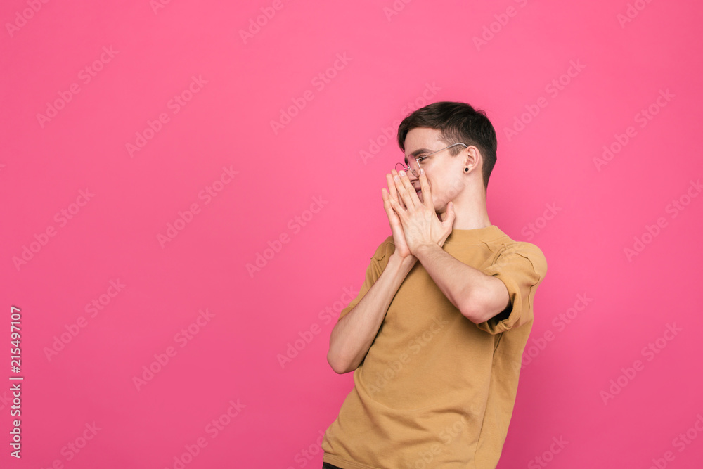 Surprised boy looking to the side standing on a pink background Surprised boy looking to the side standing on a pink background
