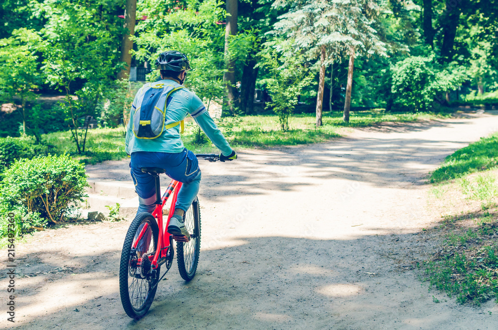 Obraz premium Cyclist in helmet on orange bike riding in park