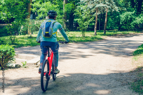 Fototapeta Naklejka Na Ścianę i Meble -  Cyclist in helmet on orange bike riding in park