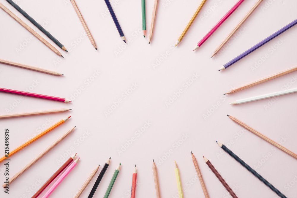 Bright colored pencils lined around the perimeter of the pink background.