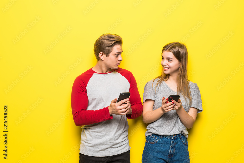 Happy couple looking at smartphone isolated on yellow background Happy couple looking at smartphone isolated on yellow background