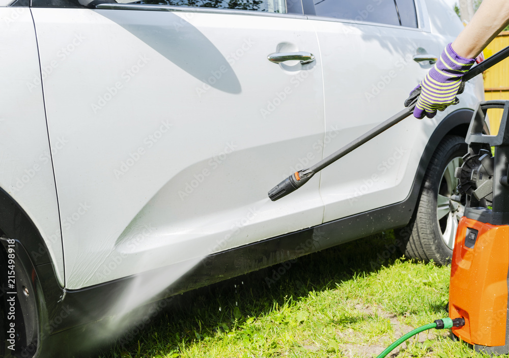 Fototapeta premium Manual car wash with pressurized water in car wash outside. Summer Car Washing. Cleaning car using high pressure water. Car detailing. Hand washer.