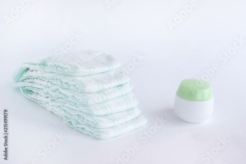 Baby diapers on a white background and a jar with baby cream