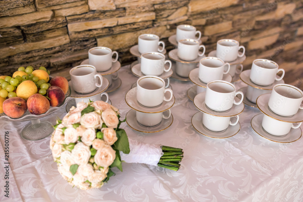View of the served for decorated table with tea set cups and wedding bouquet