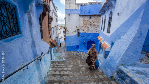 Unidentified woman walking in blue medina of Chefchaouen city in Morocco, North Africa © CanYalicn