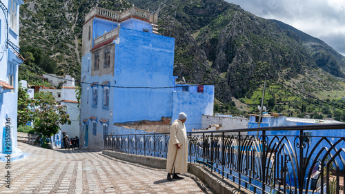 Unidentified man walking in blue medina of Chefchaouen city in Morocco, North Africa