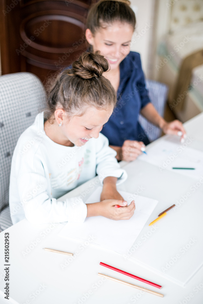 Happy family. Mother and daughter together paint and draw. Adult woman helps the child girl