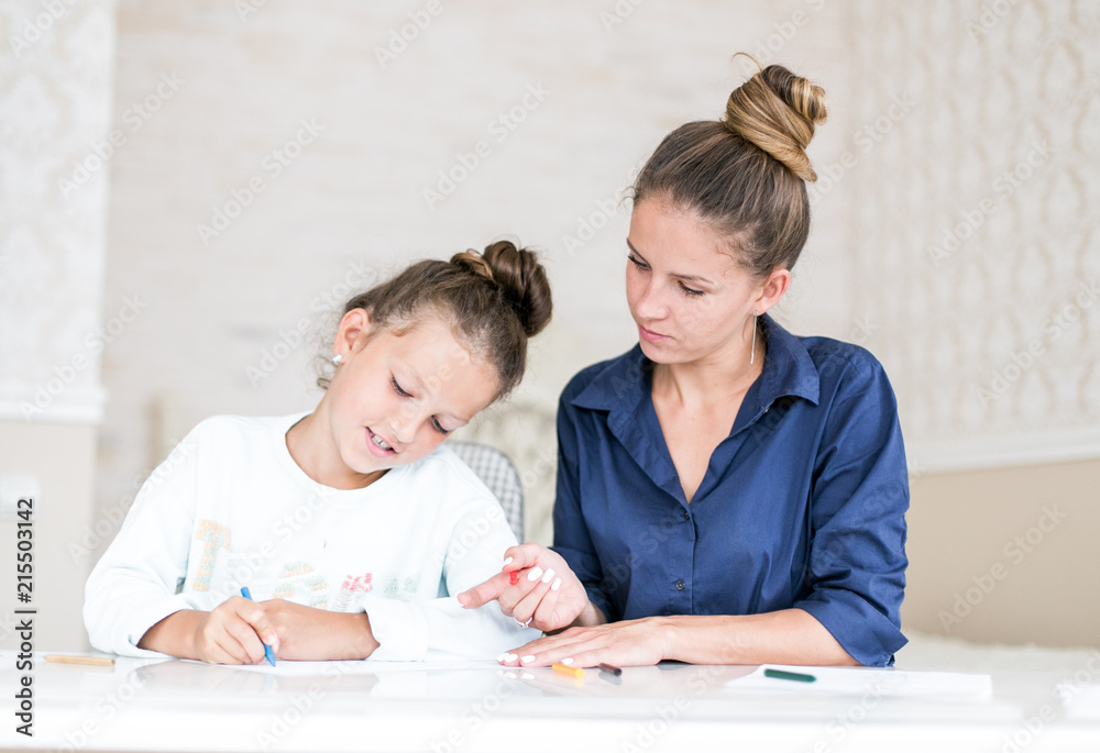 Happy family. Mother and daughter together paint and draw. Adult woman helps the child girl Happy family. Mother and daughter together paint and draw. Adult woman helps the child girl