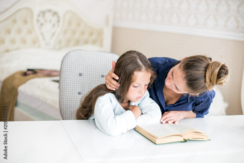 happy family mother and daughter read a book in the evening at home. the concept of family comfort and family relations happy family mother and daughter read a book in the evening at home. the concept of family comfort and family relations