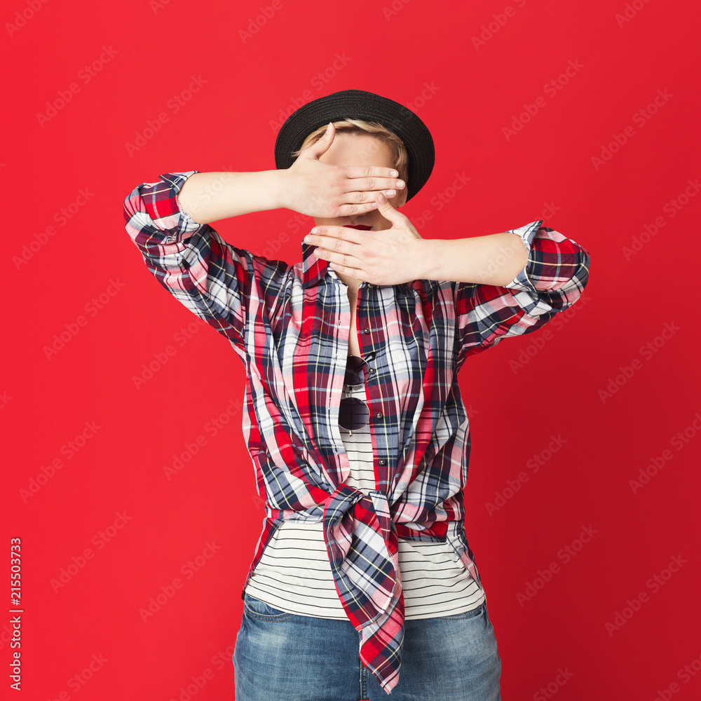 Fashion girl hiding behind hands, red background Fashion girl hiding behind hands, red background