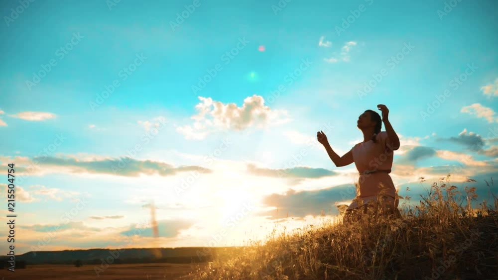 Girl folded her hands in prayer silhouette at sunset. woman praying on her knees. slow motion video. lifestyle Girl folded her hands in prayer pray to God. the girl praying asks forgiveness for sins