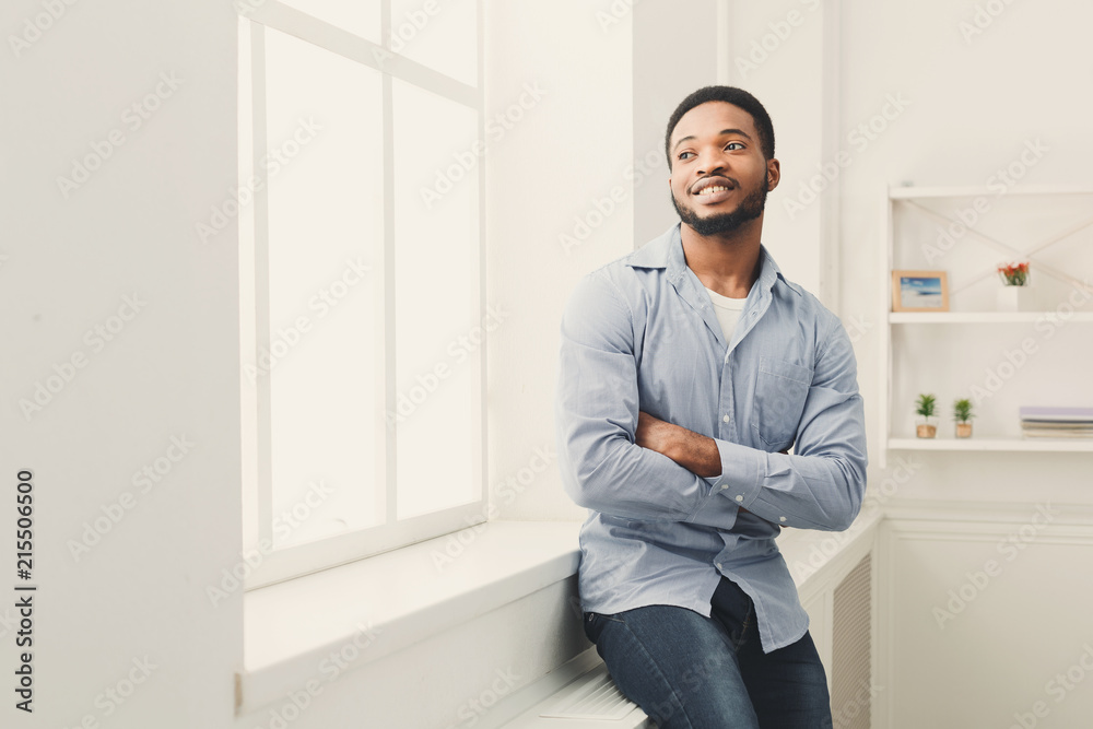 Young happy black man posing at window