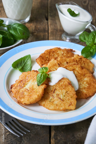 Fried potato fritters with sour cream and basil